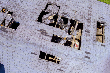 Aerial top close up view of shingles being blown off a roof and other roof damage
