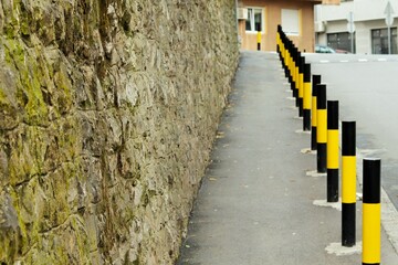 Pavement for pedestrians, fenced off from the carriageway for safety with bright posts - obrazy, fototapety, plakaty