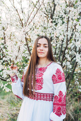 young beautiful Ukrainian woman in vyshyvanka  - ukrainian national clothes. Woman in countryside near the blossoming tree.  Stand with Ukraine  