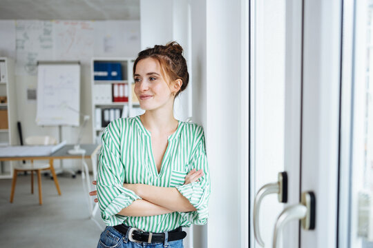 Young Businesswoman Standing At Window Looking To The Side