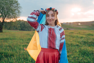 portrait of young Ukrainian woman in vyshyvanka  - ukrainian national clothes. She is holding ukrainian flag - symbol of freedom and independence. Stand with Ukraine