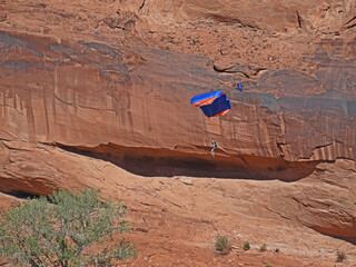 Handglides float down from the sky against colorful rock.