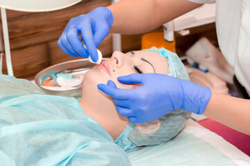 Lip augmentation. Beautician injects hyaluronic acid into the lips of a girl with a syringe. The...
