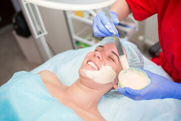 The girl at the beautician makes spa treatments, massage, facial cleansing and a mask for the skin. Cosmetic procedures in a beauty salon, facial skin care for rejuvenation.