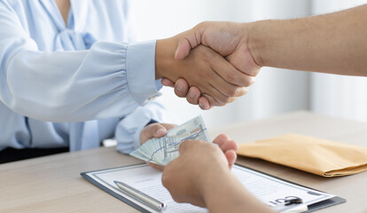 Shaking hands with congratulations on an evil plan, Businessmen give dollars to bribe employees in signing contracts to buy illegal land and real estate, corruption and Bribery concept.