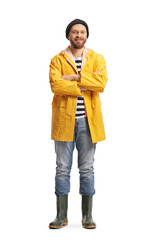 Naklejka premium Full length portrait of a fisherman in a yellow raincoat and rubber boots