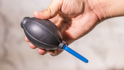 Close up male hand holding a manual hand air blower on abstract white background