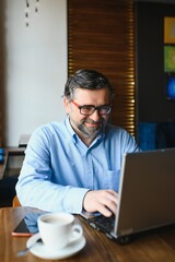 Senior male freelancer working on laptop in cafe. remote work concept.