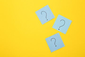 Memo pieces of paper with question marks on a yellow background. Business, psychology, answers to...