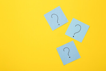 Memo pieces of paper with question marks on a yellow background. Business, psychology, answers to questions concept