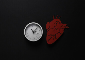 Heartbeat. Anatomical heart with a clock on a black background