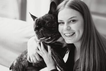 beautiful girl, smiling and sitting on floor near French bulldog