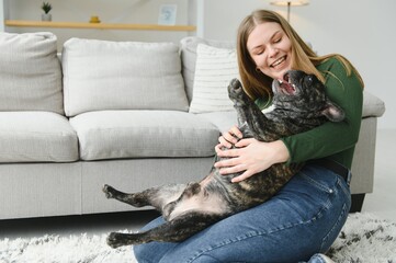Female owner playing with joyful dog at home. Playing with dog concept
