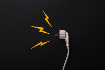 Danger of short circuit. Electric plug with sparks cut out of paper on a black background