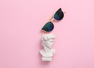 David bust with sunglasses on a pink background. Minimal pop culture layout. Top view
