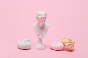 Venus bust with sweet meringue isolated on pink background.