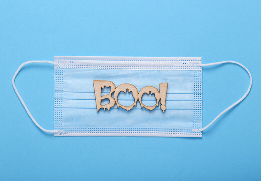 Halloween, covid 19 pandemic. Face mask with the word boo! on a blue background