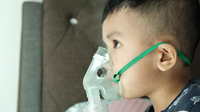 A handheld close up footage of a boy using home nebulizer machine for treating asthma, bronchitis and illness related to respiratory