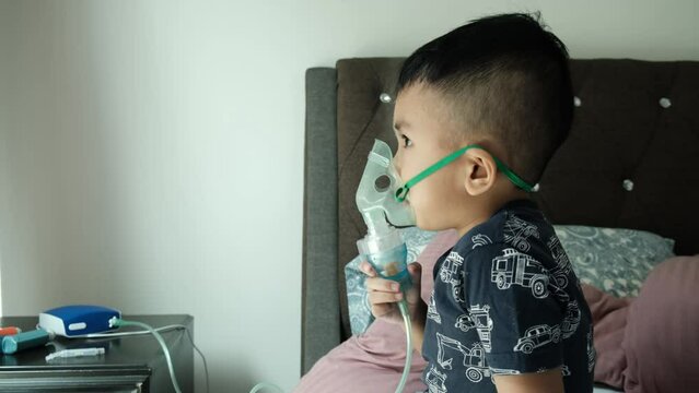 Handheld footage of a boy using home nebulizer machine for treating his asthma