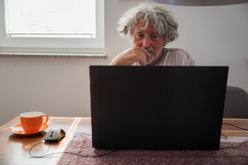 Senior man using laptop computer for a zoom meeting with family