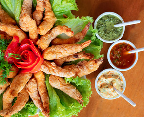 breaded shrimp on a tray with decoration made with lettuce and tomato vegetables, with accompaniments of various sauces 