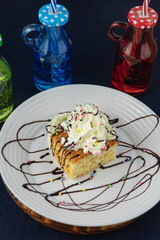 Lemon cake with cream, colored sugar flakes and chocolate syrup