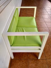 A green sofa chair with a minimalist design placed in the corridor in front of the school classroom.
