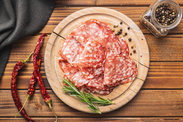 Sliced italian salami sausage with peppercorn on cutting board.