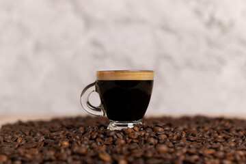 black coffee in a transparent cup on a coffee bean table with a marble base. 
