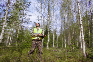 ecologist works with a computer in a young birch forest.