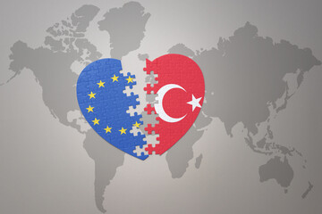 puzzle heart with the national flag of european union and turkey on a world map background. Concept.