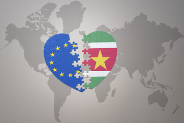 puzzle heart with the national flag of european union and suriname on a world map background. Concept.
