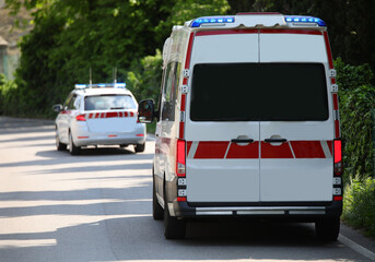 Ambulance van with flashing sirens running on the road and a medical car in front of it during the...