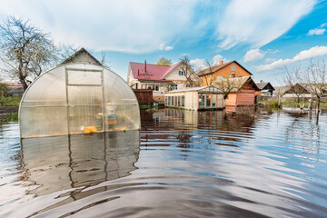 Vegetable Garden Beds In Water During Spring Flood floodwaters during natural disaster. Greenhouse Hothouse in Water deluge During A Spring Flood. inundation River. - obrazy, fototapety, plakaty