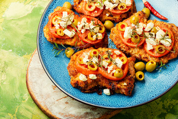 Meat schnitzel with cheese, olives and tomato