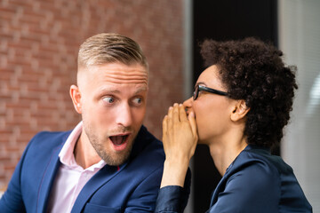 Businesswoman Whispering Into Male Partner's Ear
