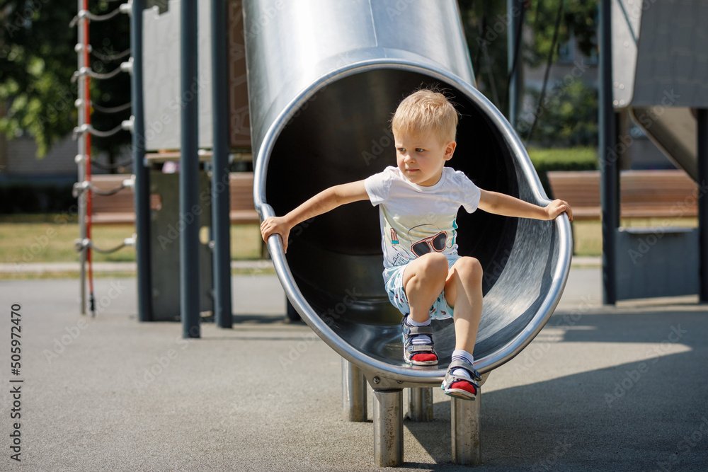 Wall mural a boy on a metal enclosed circular tunnel slide. a child riding the playground slide.