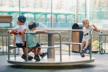 Kids play on playground during summer vacation. Carousel for children in summer in the park.