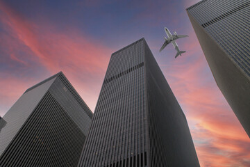 Look up view to the Manhattan skyscrapers in New York with colorful sky and air craft passing between buildings. 