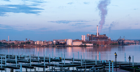 Sunrise over waterfront industrial center with smoke blowing from factory smokestacks in Baltimore...