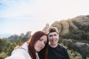  young girls, friends and hikers, taking a selfie from the top of the mountain with their smartphone. 