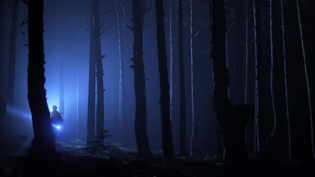 Man running in foggy forest at night.  Fear and escape.
The man with the lantern is running through the foggy forest at night.
