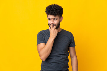 Young Moroccan man isolated on yellow background nervous and scared