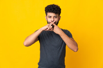 Young Moroccan man isolated on yellow background showing a sign of silence gesture