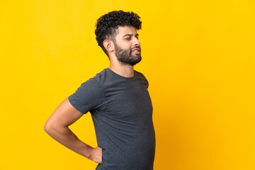 Young Moroccan man isolated on yellow background suffering from backache for having made an effort