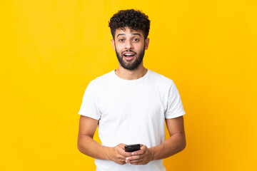 Young Moroccan man isolated on yellow background surprised and sending a message