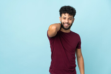 Young Moroccan man isolated on blue background laughing