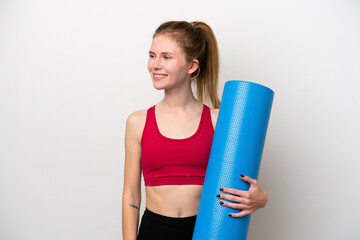 Young sport English woman going to yoga classes while holding a mat isolated on white background looking to the side and smiling © luismolinero
