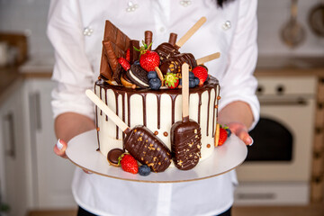 Pastry chef girl holds a beautiful delicious cake in her hands. close-up