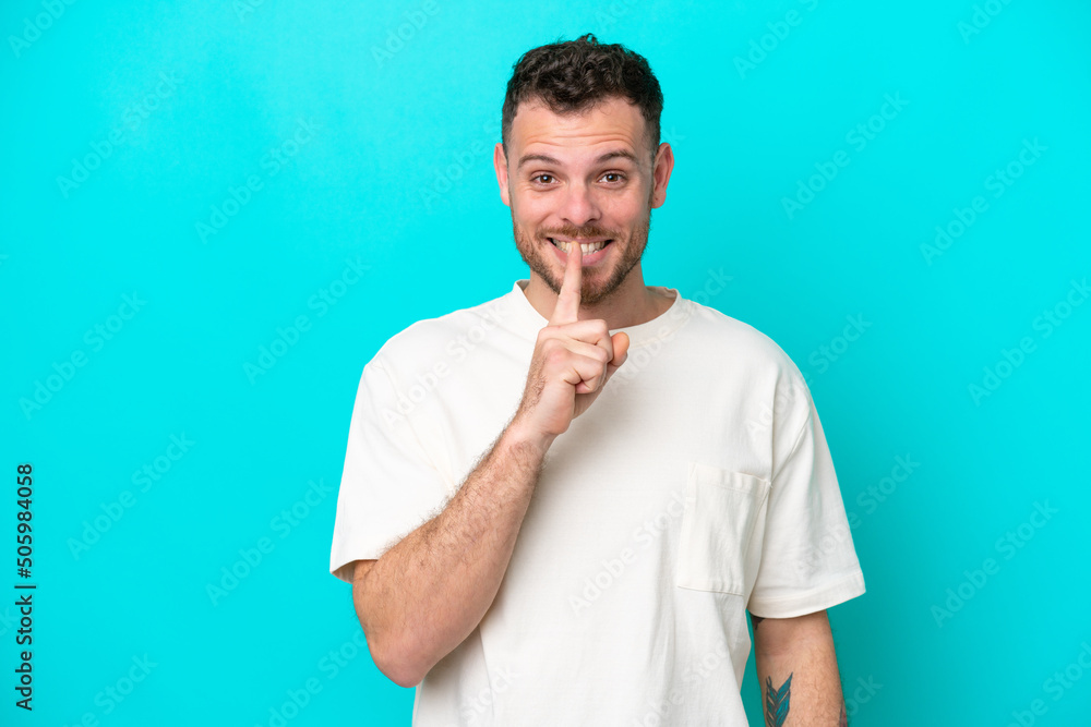 Wall mural Young Brazilian man isolated on blue background showing a sign of silence gesture putting finger in mouth